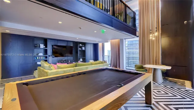 a living room with stainless steel appliances furniture a rug and a kitchen view