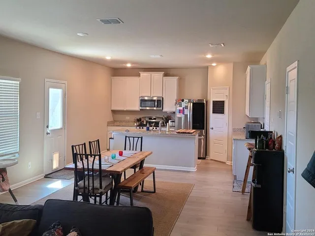 a kitchen with a dining table chairs and a refrigerator