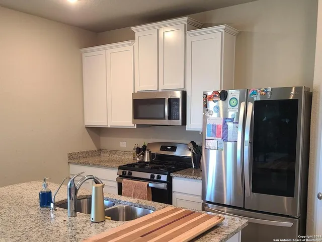 a kitchen with stainless steel appliances granite countertop a refrigerator and a stove top oven