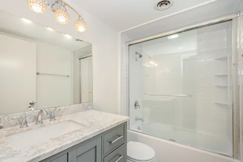 a bathroom with a granite countertop sink toilet and shower