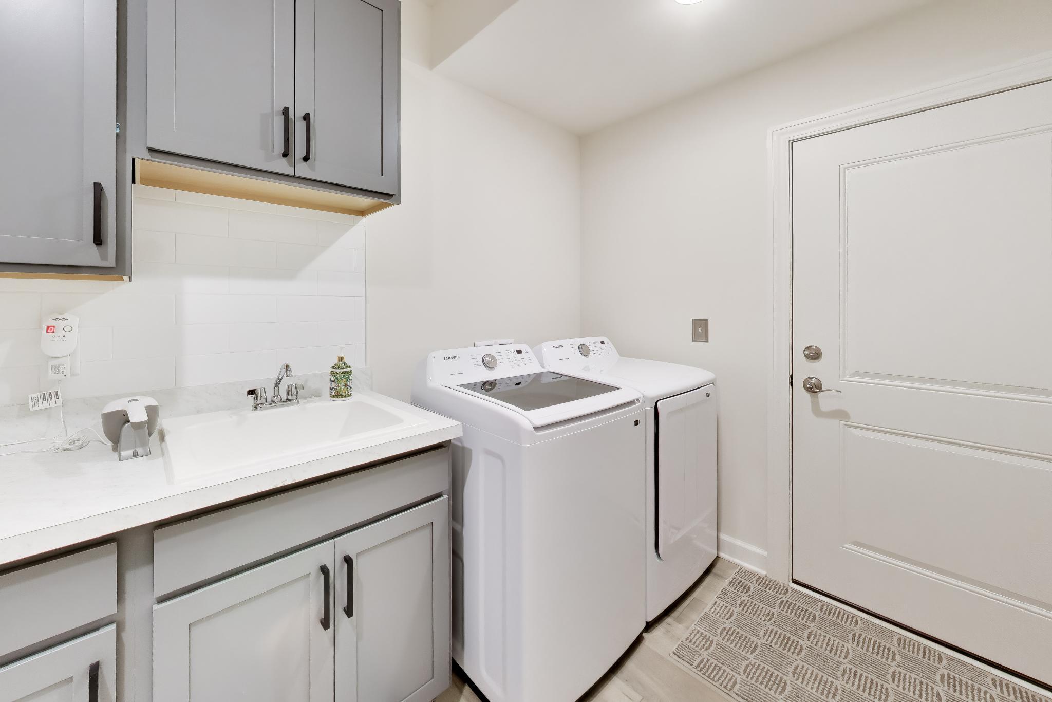 2730 Harbor Court Delavan, WI 53115 - Photo 24 of 47 Main-level laundry/mudroom with utility sink, cabinet storage, washer and dryer, and direct garage entry.