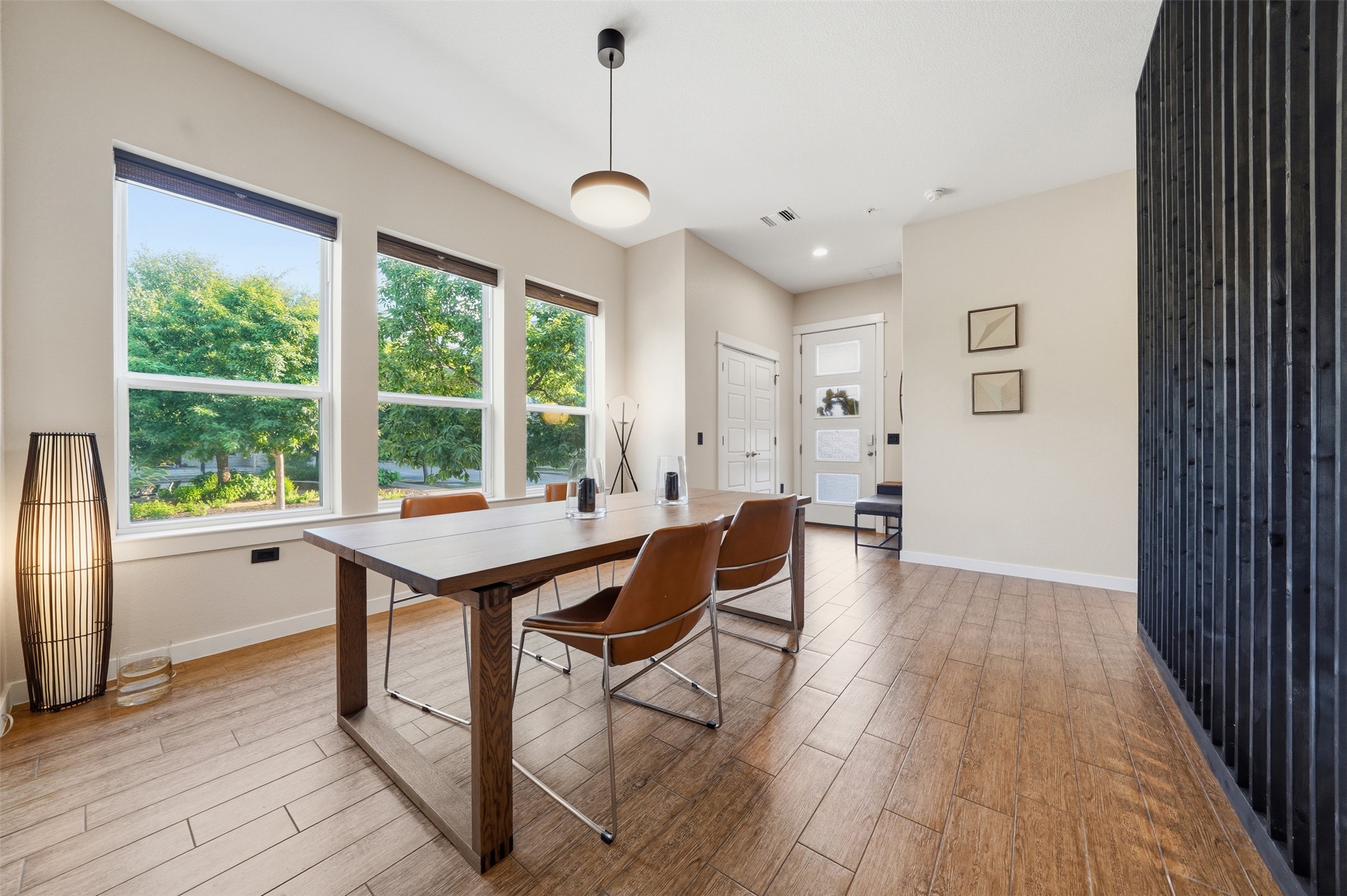 3901 Vaughan Street Austin, TX 78723 - Photo 15 of 37 Open concept dining area featuring three large windows, wood-finish flooring, a modern pendant light, and a slatted accent wall