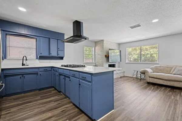 a kitchen with stainless steel appliances granite countertop a sink dishwasher stove and wooden cabinets with wooden floor