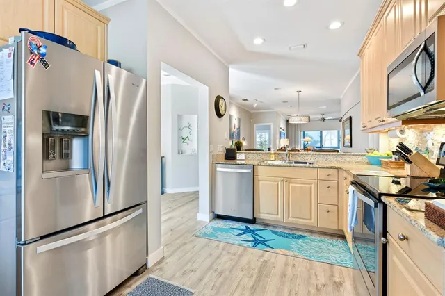 a living room with stainless steel appliances furniture a dining table and a potted plant