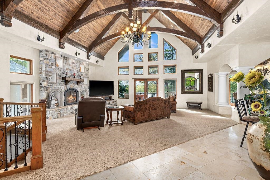 3993 Scenic View Road Moose Lake, MN 55767 - Photo 3 of 48 Living room featuring decorative columns, stone fireplace, and high vaulted ceiling with beams