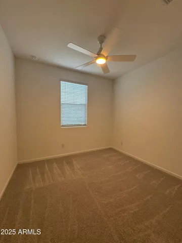 an empty room with a window and ceiling fan