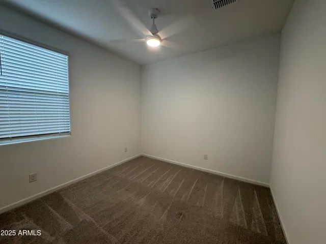 an empty room with a ceiling fan and window