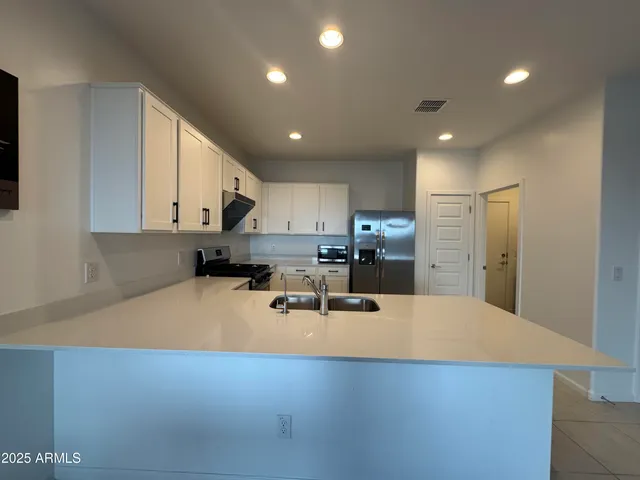 a large kitchen with stainless steel appliances a large counter top a stove and a refrigerator