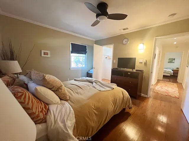 a bedroom with a bed ceiling fan and a wooden floor
