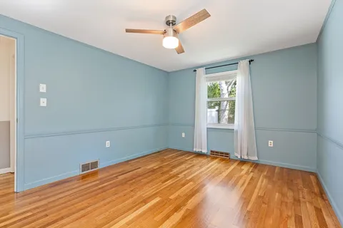 a view of a room with wooden floor and a ceiling fan