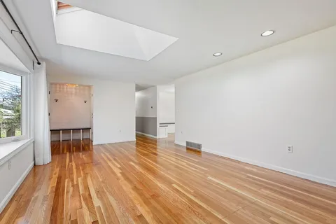 a view of empty room with wooden floor and windows