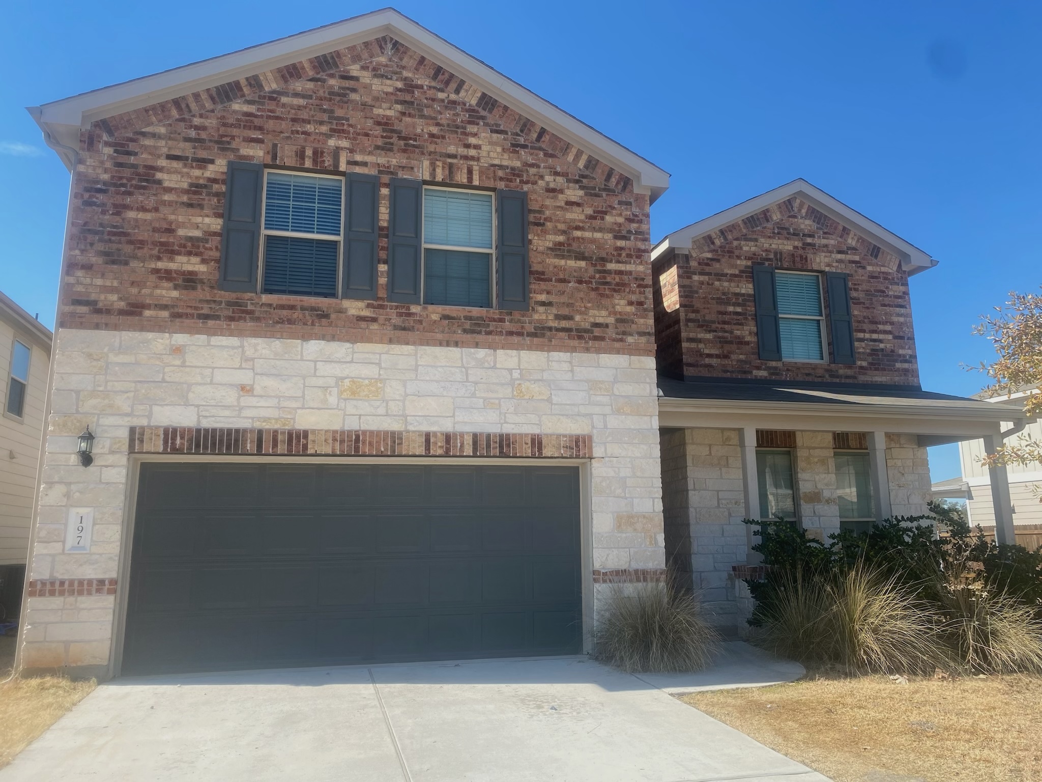197 Prairie Falcon Way Leander, TX 78641 - Photo 2 of 29 View of front of property with an attached garage, stone siding, concrete driveway, covered porch, and brick siding