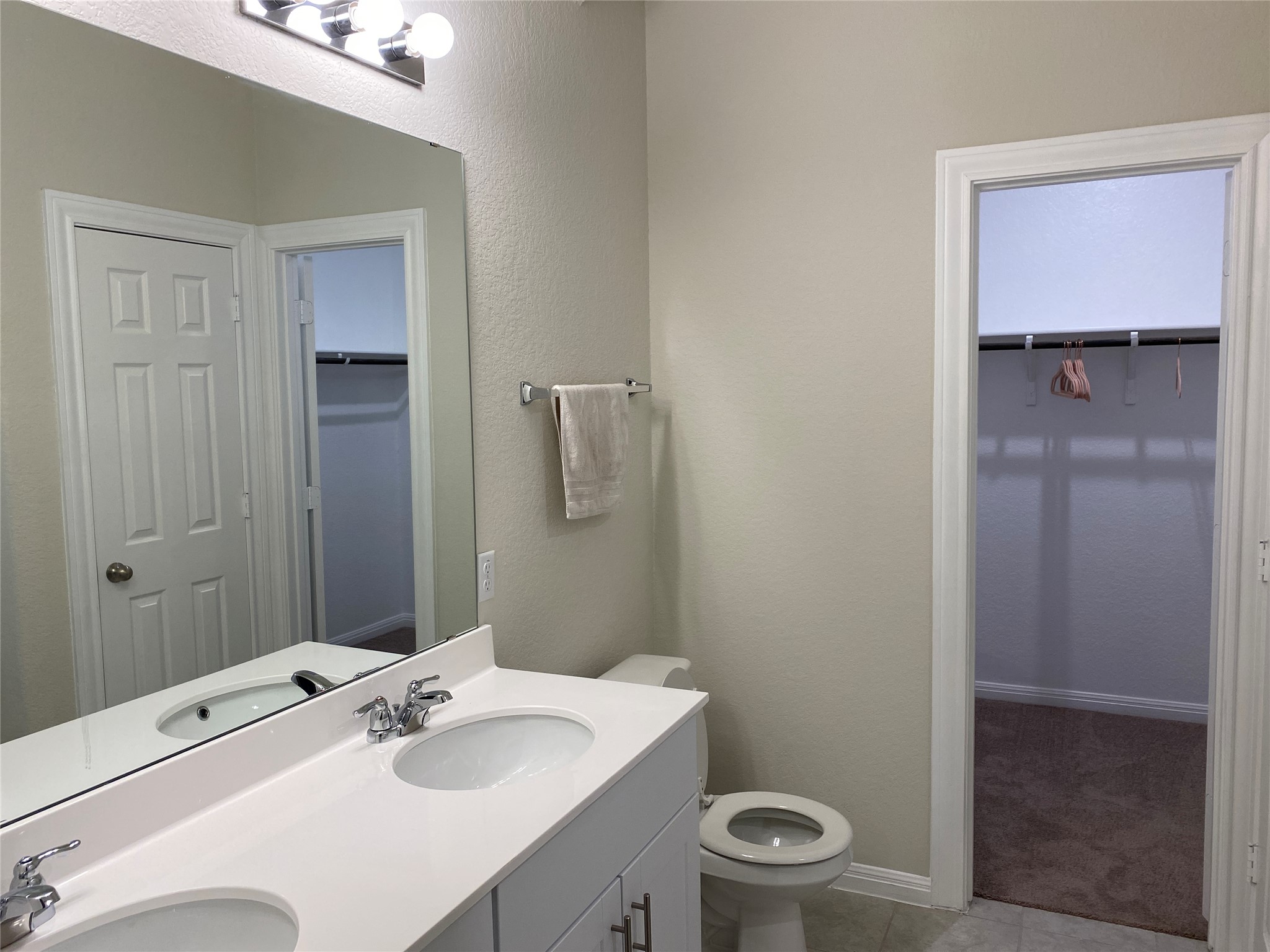 197 Prairie Falcon Way Leander, TX 78641 - Photo 23 of 29 Full bath featuring double vanity, a textured wall, a walk in closet, and light tile patterned floors
