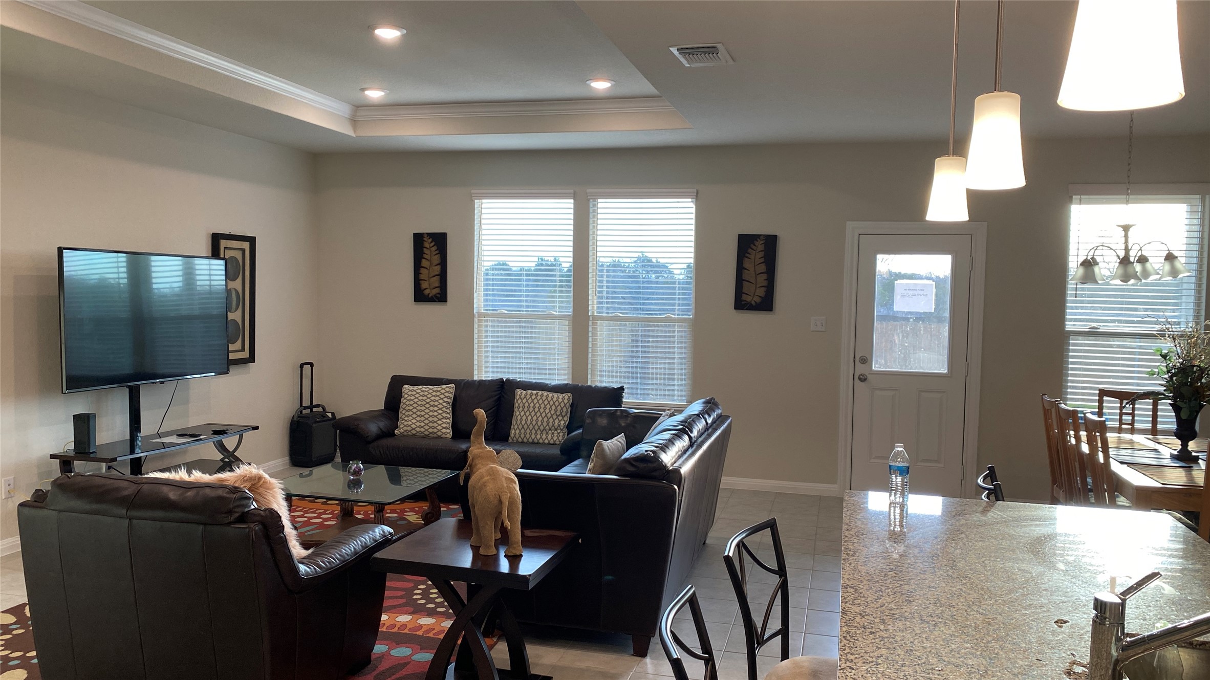 197 Prairie Falcon Way Leander, TX 78641 - Photo 3 of 29 Living room featuring crown molding, light tile patterned flooring, suspended lighting, and a tray ceiling