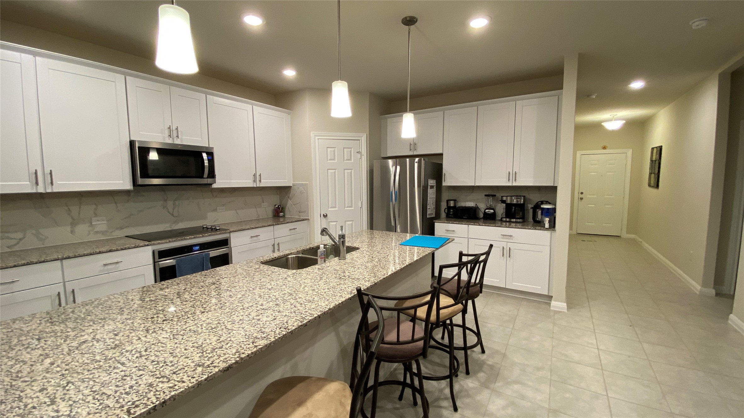 197 Prairie Falcon Way Leander, TX 78641 - Photo 5 of 29 Kitchen with backsplash, a kitchen breakfast bar, and white cabinetry
