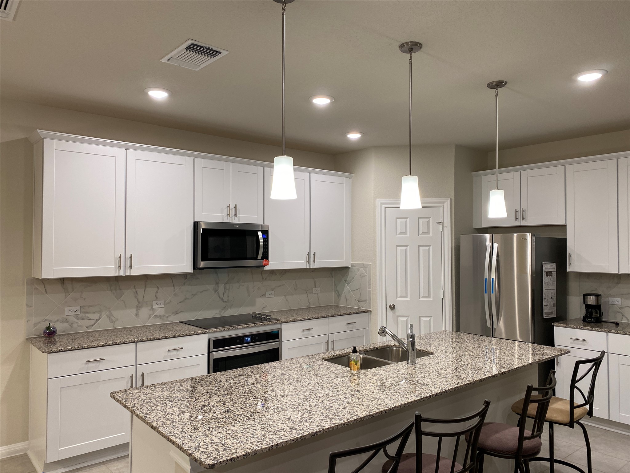 197 Prairie Falcon Way Leander, TX 78641 - Photo 8 of 29 Kitchen featuring stainless steel appliances, white cabinets, light stone counters, a breakfast bar, and tasteful backsplash