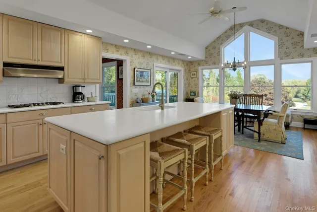 a kitchen with granite countertop a stove a sink a dining table and chairs with wooden floor