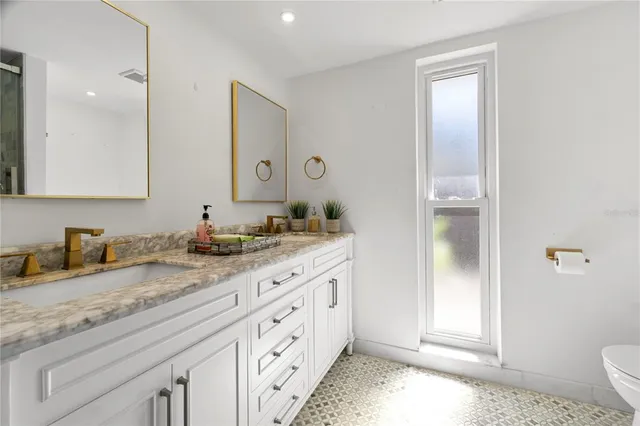 a bathroom with granite countertop a sink and a mirror