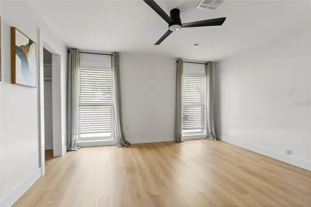 an empty room with wooden floor and windows