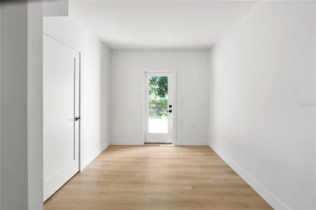 a view of an empty room with wooden floor and a window