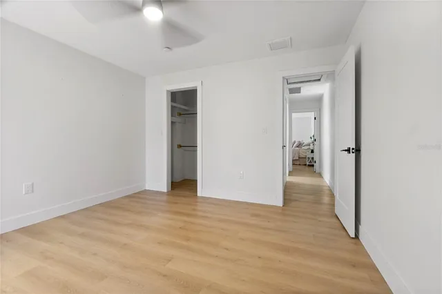 a view of a hallway with wooden floor and a bathroom