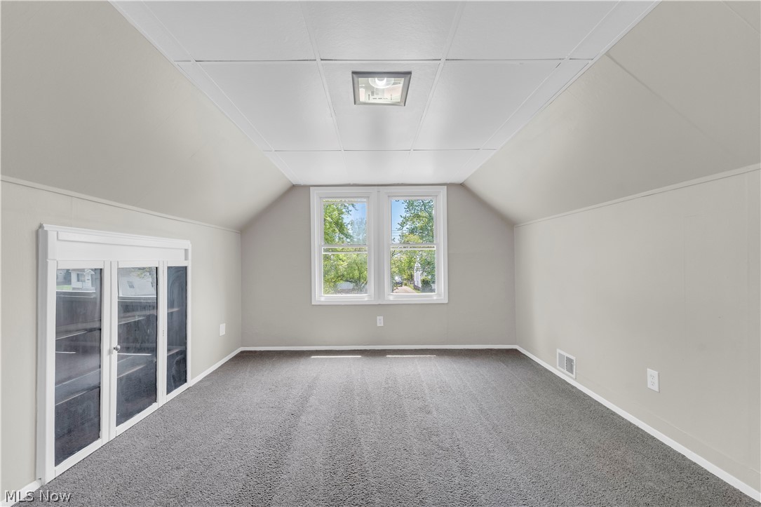 18123 McCracken Road Maple Heights, OH 44137 - Photo 19 of 27 Room featuring sloped walls, gray carpeting, and a white grid-patterned ceiling