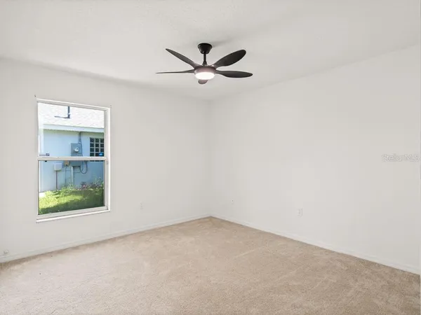 an empty room with a ceiling fan and a window
