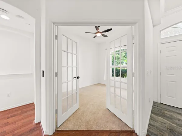 an empty room with chandelier fan and windows