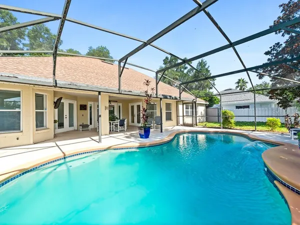 a view of pool with lawn chairs and floor to ceiling window
