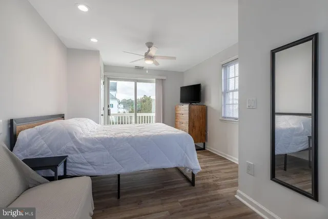 a bedroom with a bed a mirror on desk and a window