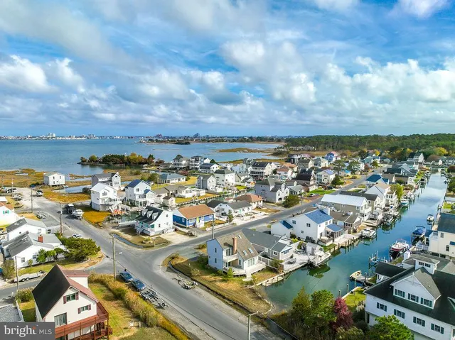 an aerial view of a city with lots of residential buildings ocean and mountain view in back