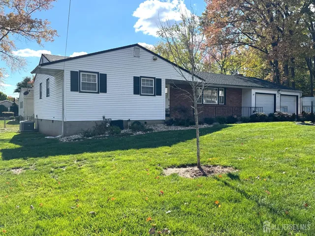 a view of a house with a yard and a large tree