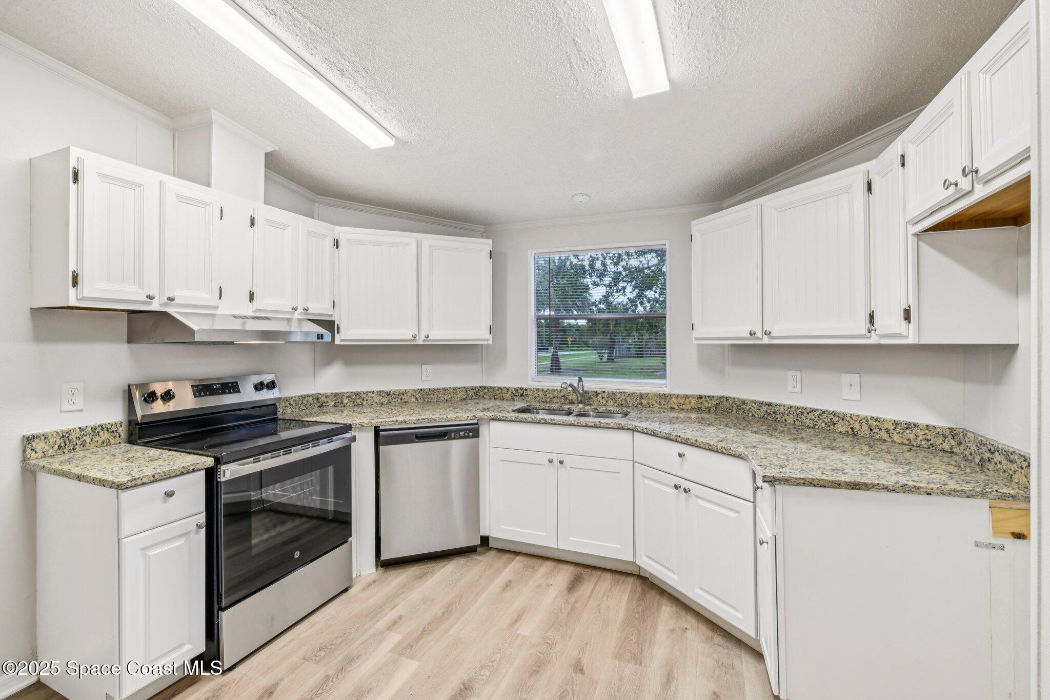 7070 Bismark Road Cocoa, FL 32927 - Photo 11 of 33 a kitchen with granite countertop white cabinets and white stainless steel appliances