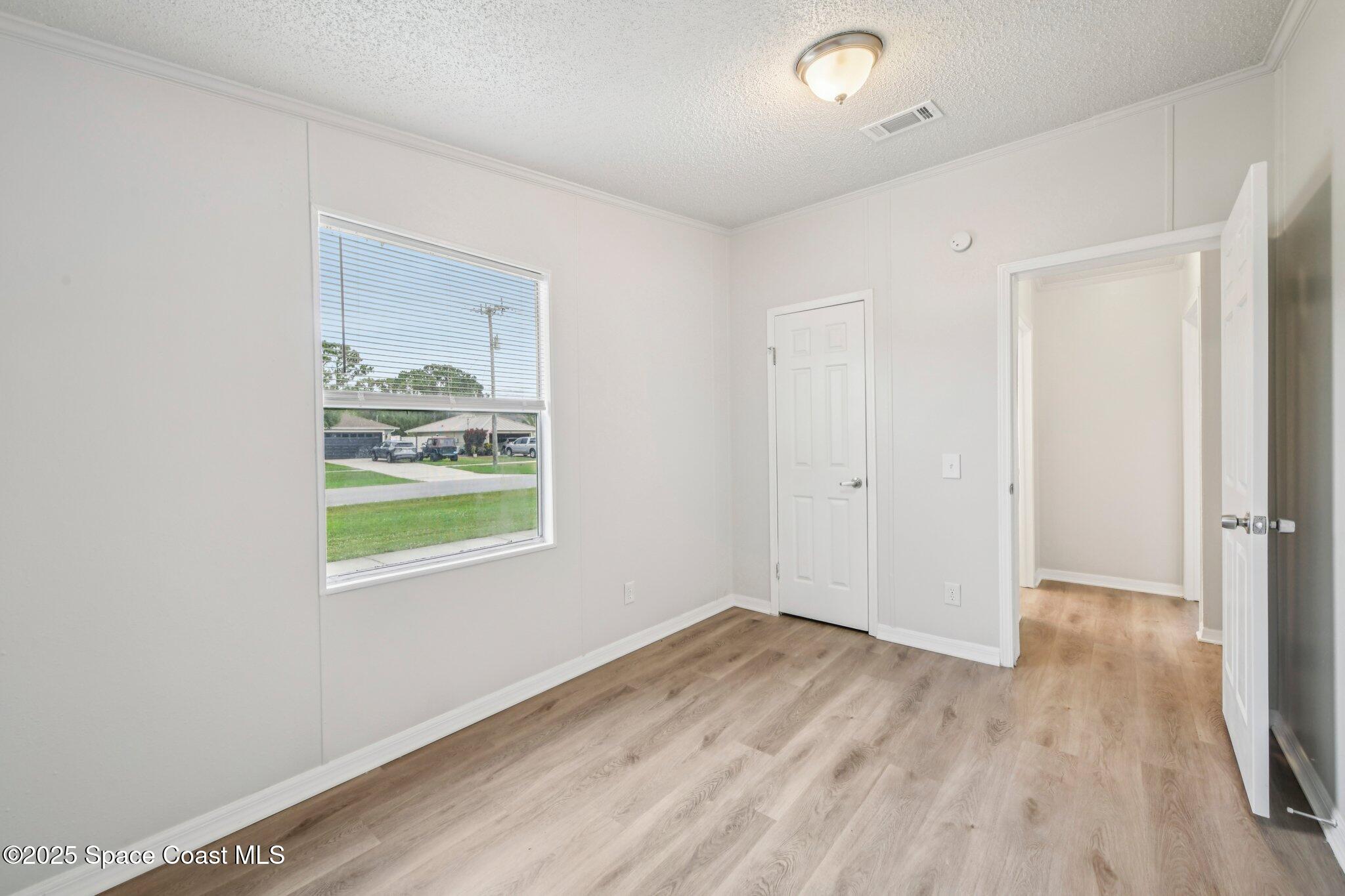 7070 Bismark Road Cocoa, FL 32927 - Photo 21 of 33 a view of an empty room with wooden floor and a window