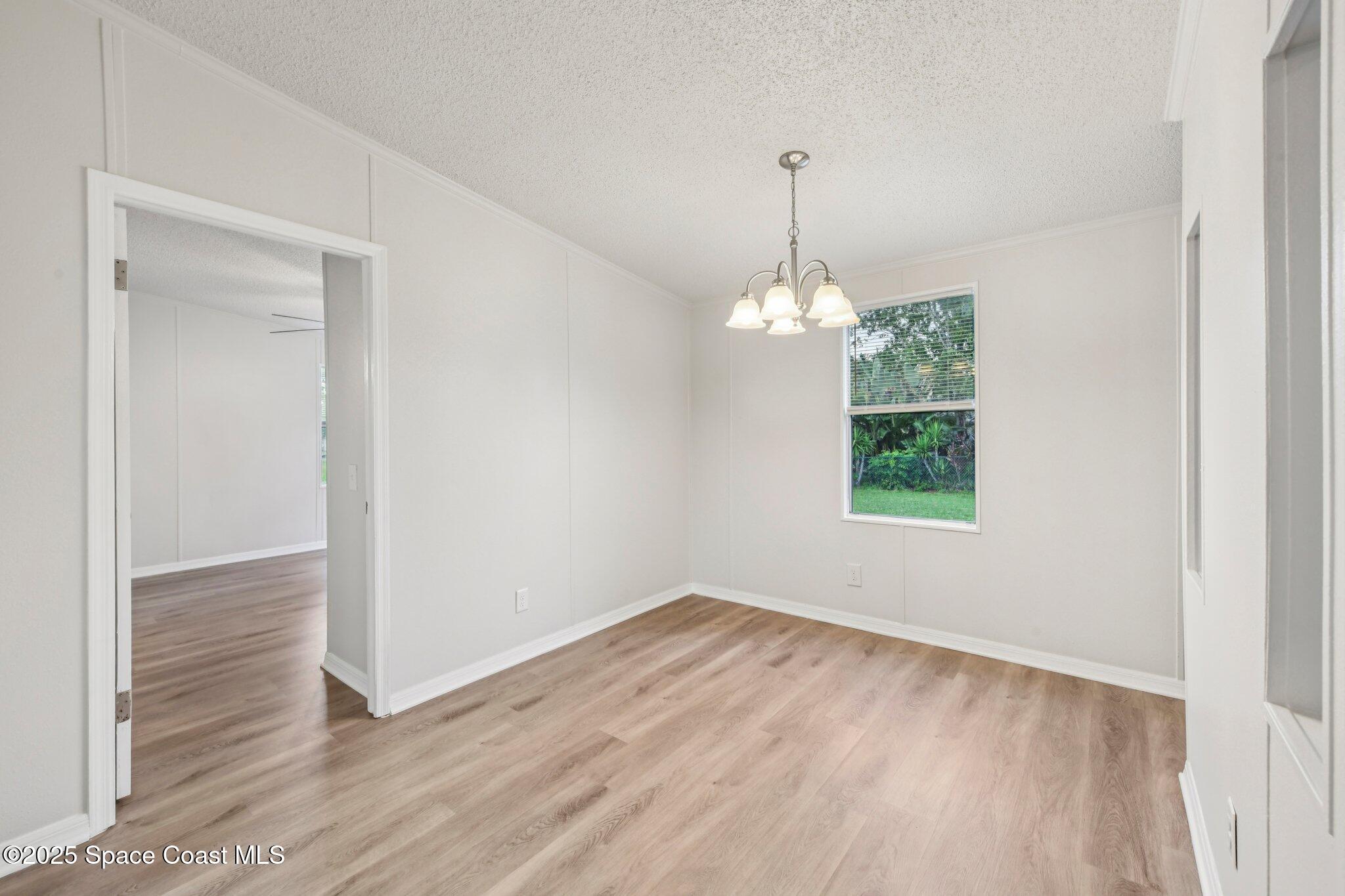 7070 Bismark Road Cocoa, FL 32927 - Photo 27 of 38 an empty room with wooden floor chandelier and windows