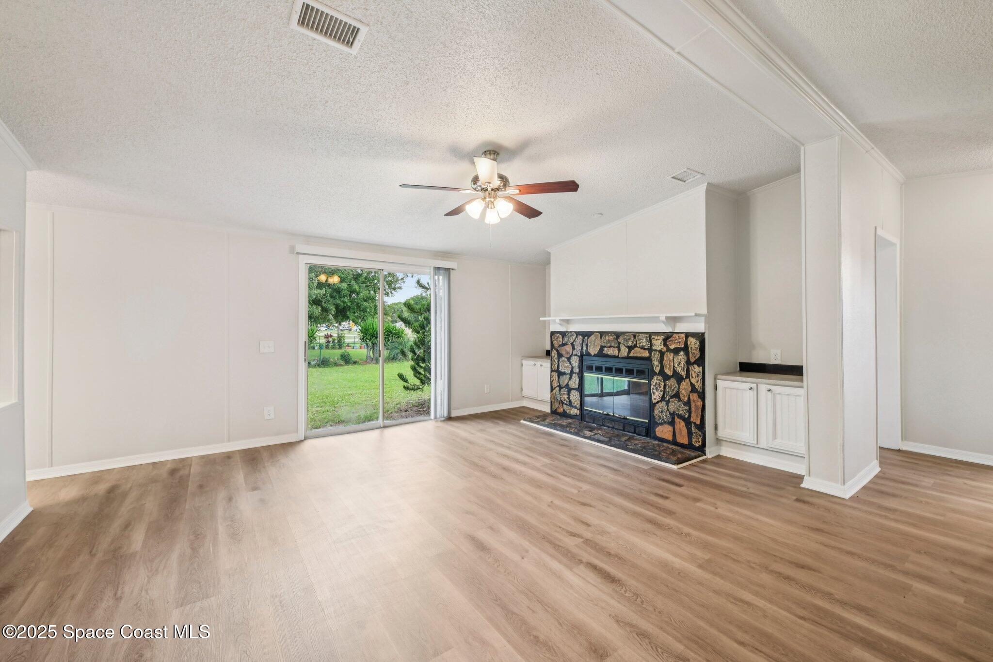 7070 Bismark Road Cocoa, FL 32927 - Photo 6 of 38 an empty room with wooden floor a ceiling fan and windows