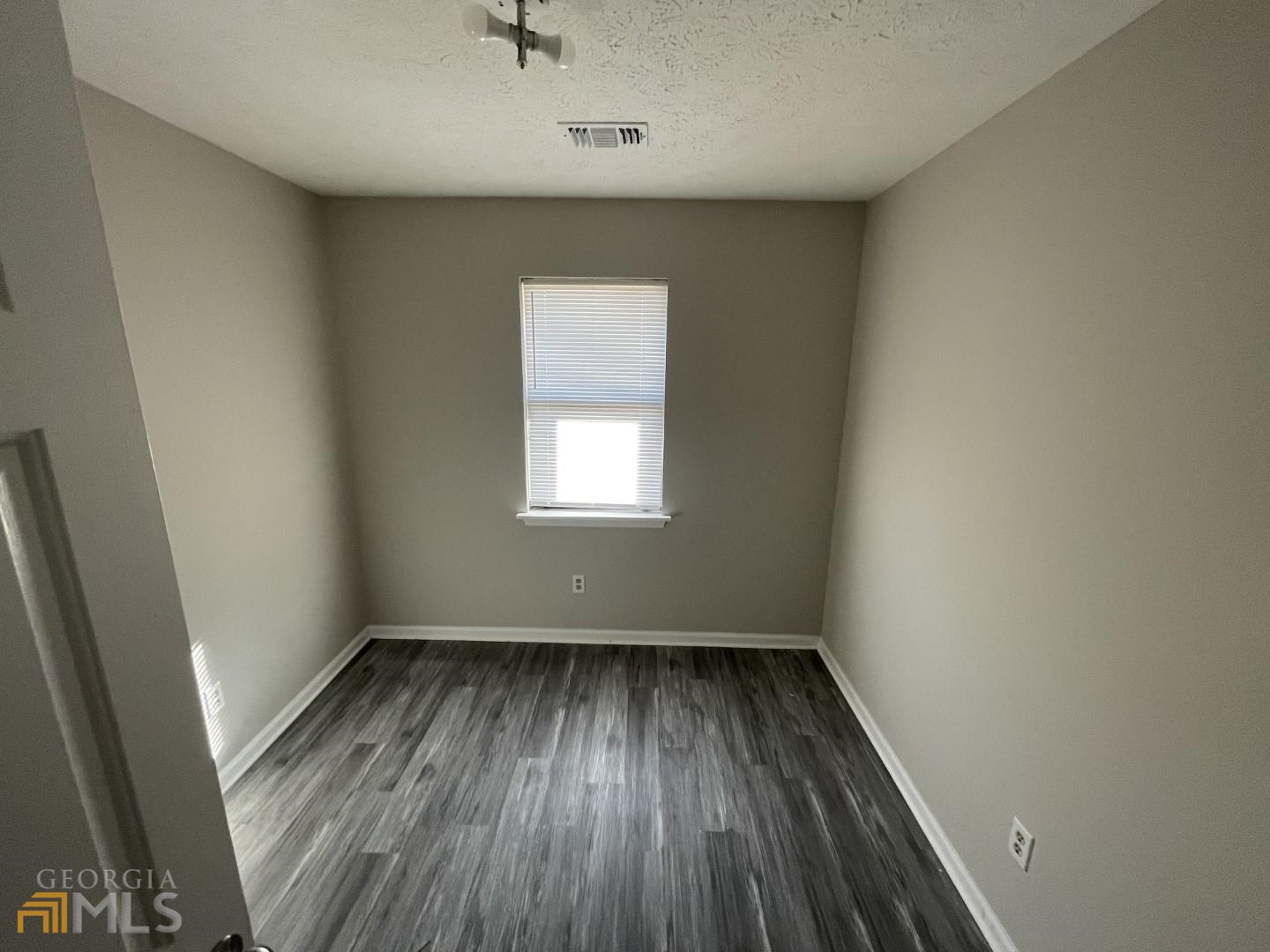 307 Pelly Avenue, Unit 307 Griffin, GA 30223 - Photo 12 of 16 an empty room with wooden floor and windows