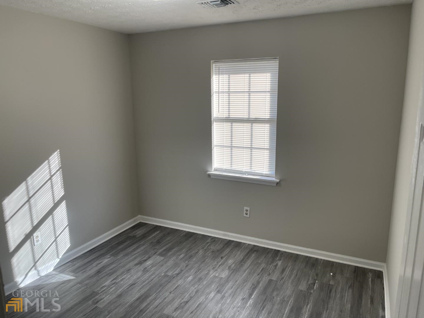307 Pelly Avenue, Unit 307 Griffin, GA 30223 - Photo 15 of 16 an empty room with wooden floor and windows