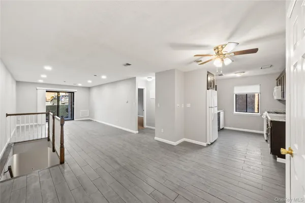 a view of a livingroom with a fireplace a ceiling fan and wooden floor