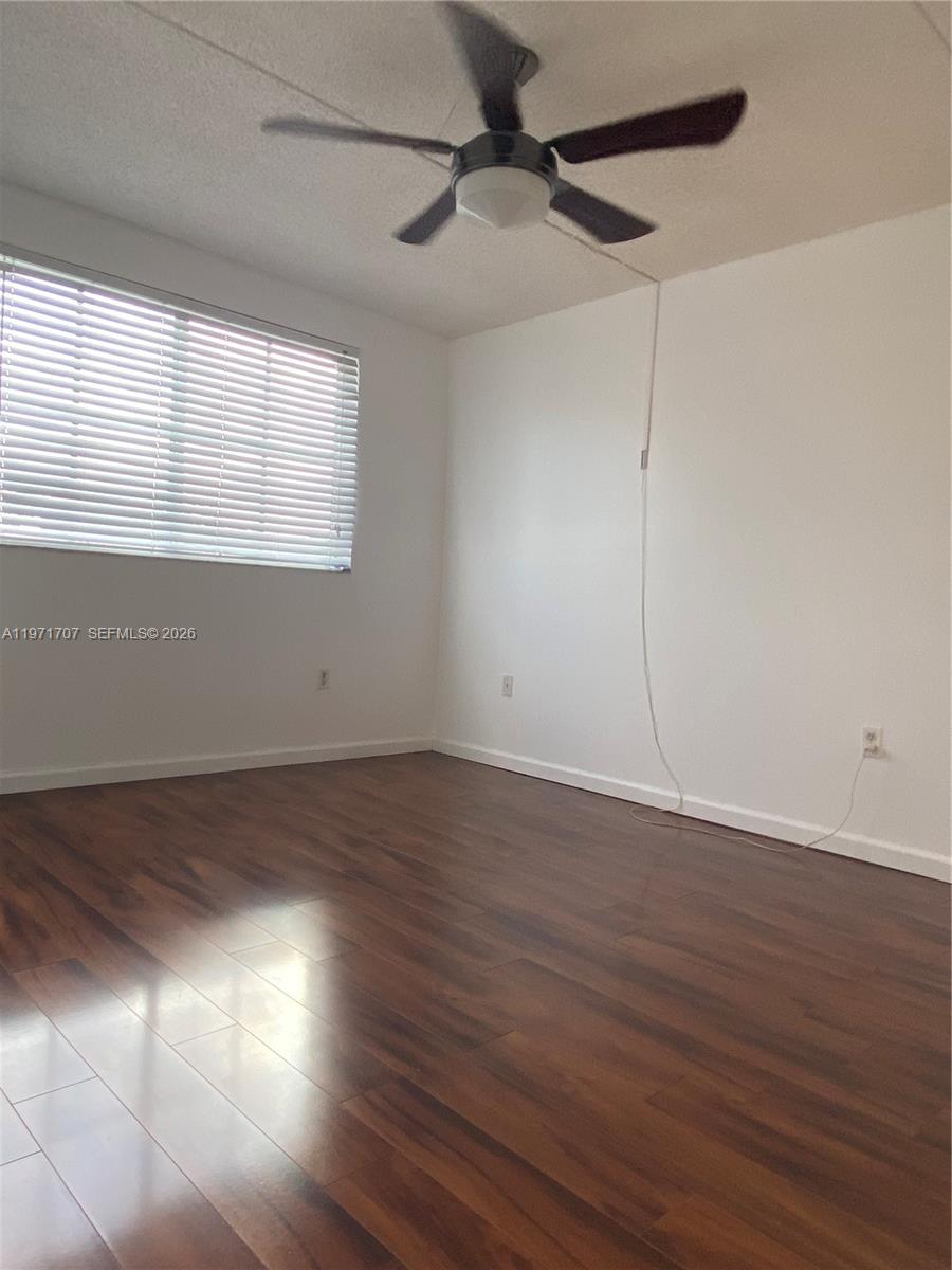 6155 Northwest 186th Street, Unit 308 Hialeah, FL 33015 - Photo 11 of 34 an empty room with wooden floor fan and windows