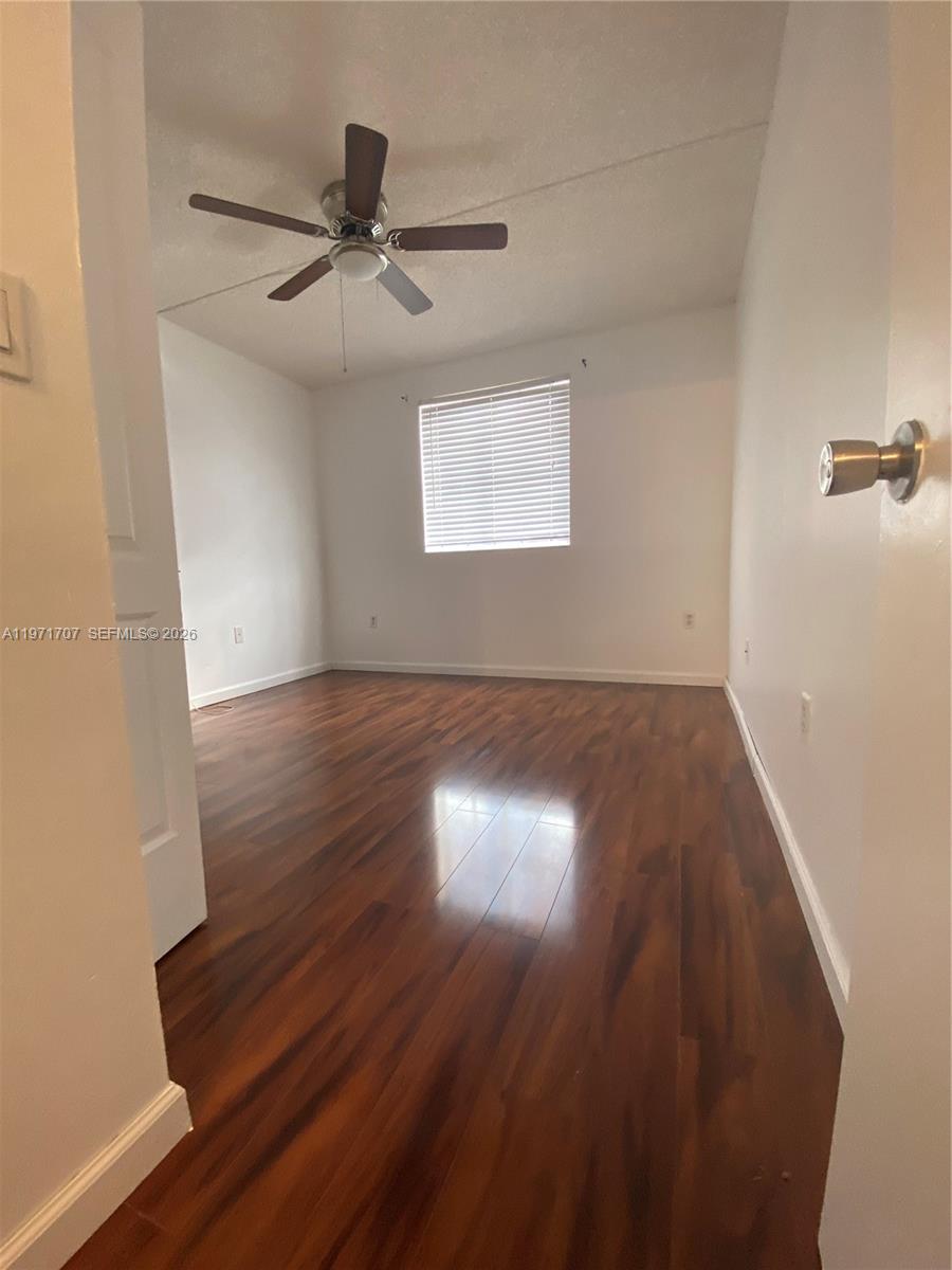 6155 Northwest 186th Street, Unit 308 Hialeah, FL 33015 - Photo 17 of 34 an empty room with wooden floor chandelier fan and windows