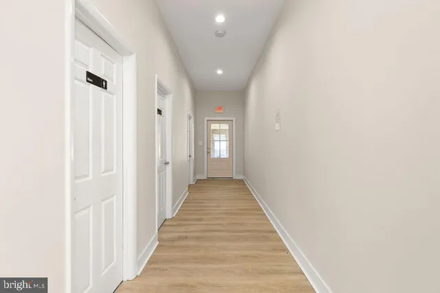 a view of a hallway with wooden floor and a living room