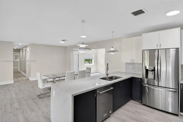 a large kitchen with stainless steel appliances kitchen island granite countertop a stove a sink dishwasher and a refrigerator with wooden floor