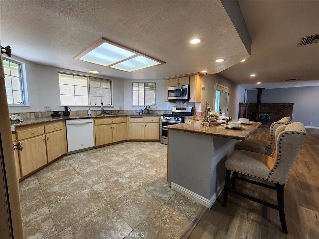 28035 Bonanza Road Barstow, CA 92311 - Photo 20 of 29 a kitchen with kitchen island granite countertop wooden cabinets a sink a stove a counter top space and a center island