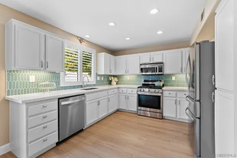 a kitchen with granite countertop white cabinets and stainless steel appliances