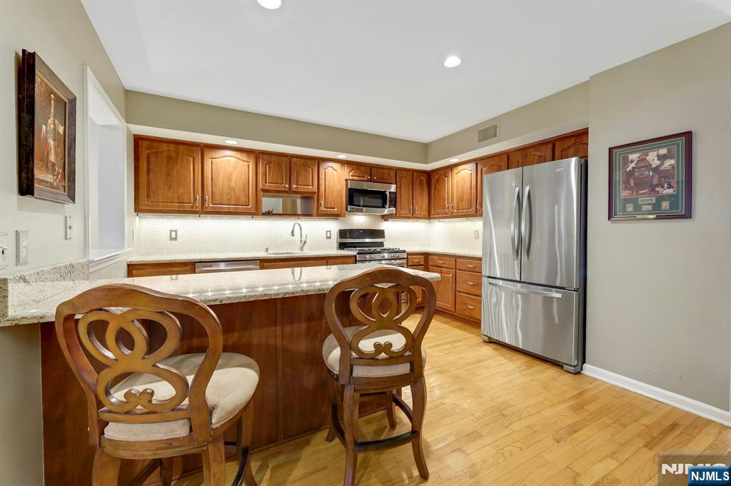 56 Longfellow Lane Mahwah, NJ 07430 - Photo 15 of 33 a kitchen with stainless steel appliances granite countertop a refrigerator a stove a sink a dining table and chairs with wooden floor