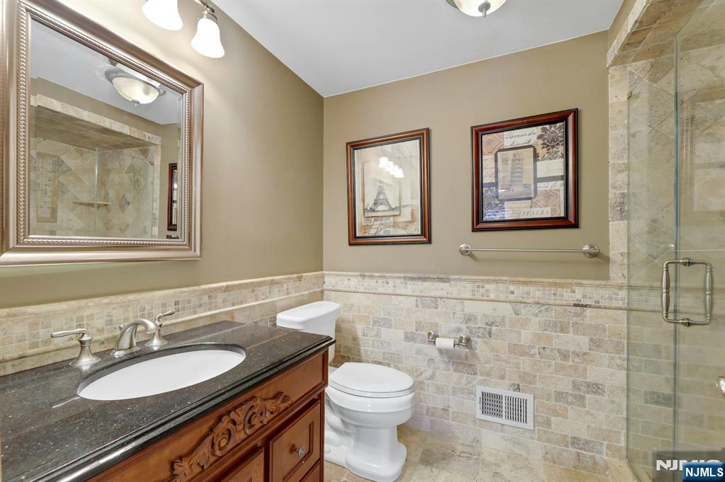 56 Longfellow Lane Mahwah, NJ 07430 - Photo 22 of 33 a bathroom with a granite countertop toilet a sink a mirror and a shower
