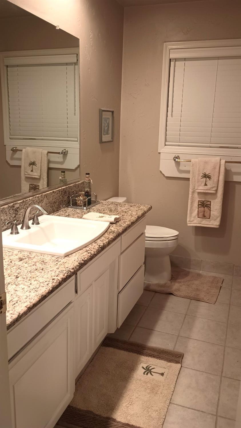 14728 Huntington Road Madera, CA 93636 - Photo 36 of 37 a bathroom with a granite countertop sink a toilet and mirror