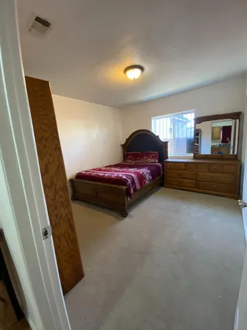 a spacious bedroom with a bed and a dresser