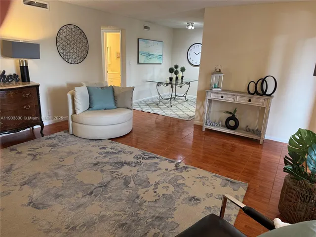 a living room with furniture a clock and wooden floor